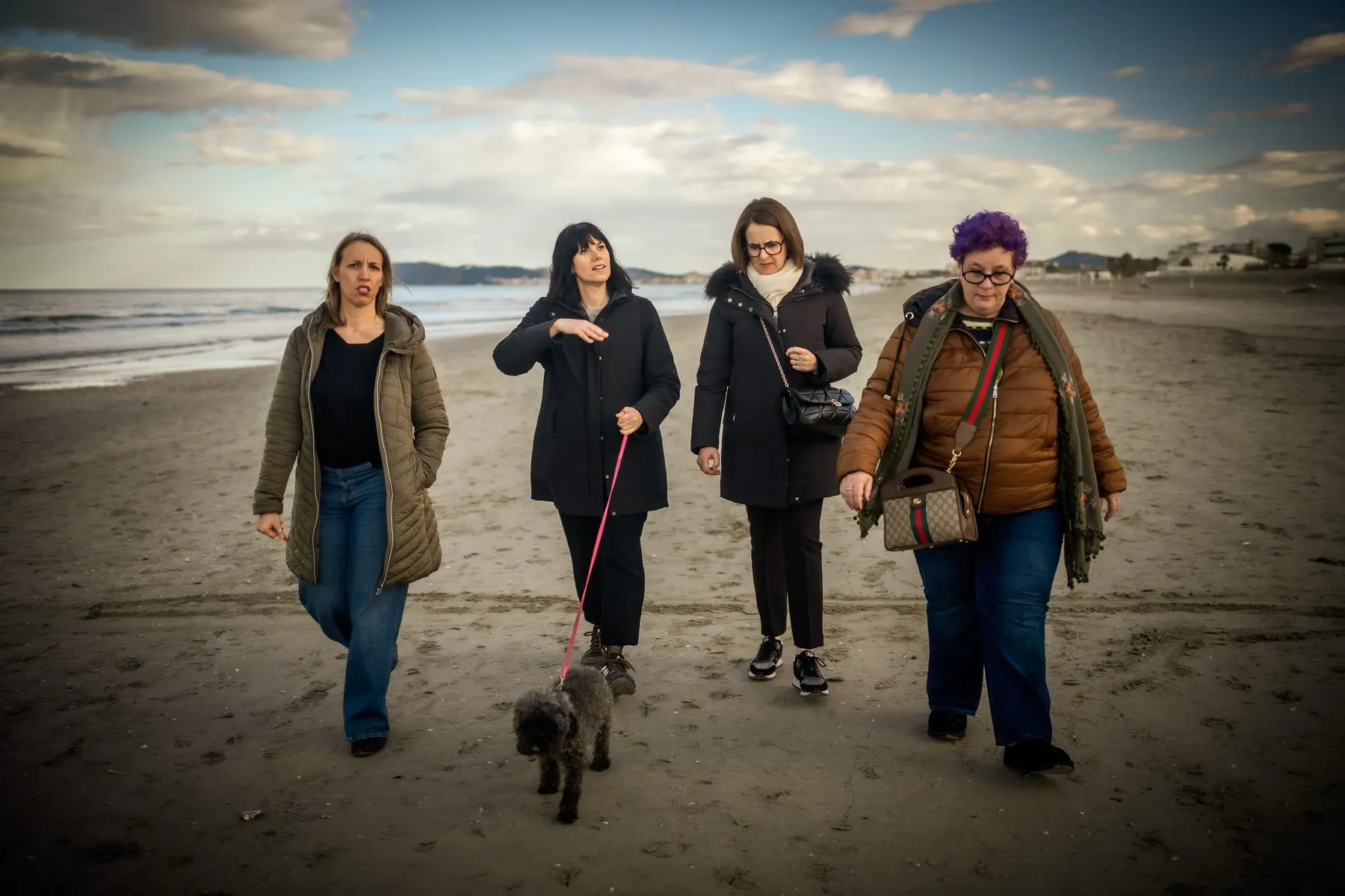 Quattro donne camminano insieme sulla spiaggia